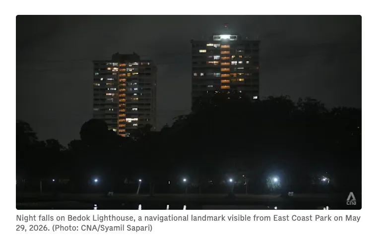Bedok Lighthouse glowing at night atop the 25-storey Lagoon View condominium, seen across the water from East Coast Park